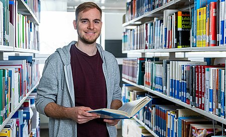 Bibliotheksnutzer zwischen den Bibliotheksregalen